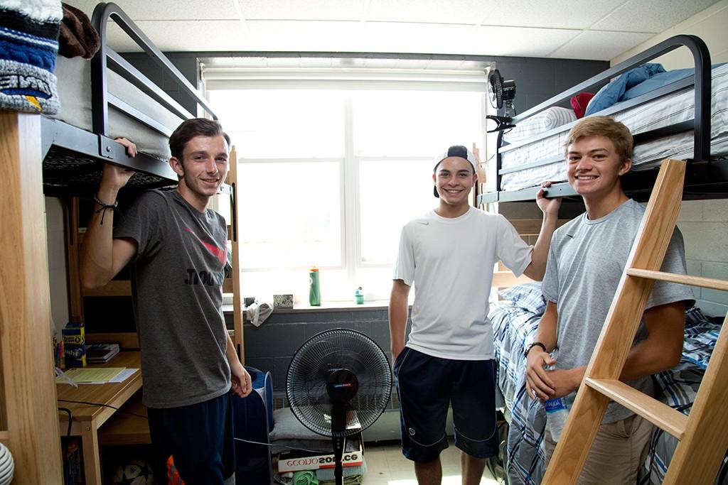 三名东北大学学生站在宿舍的双层床旁